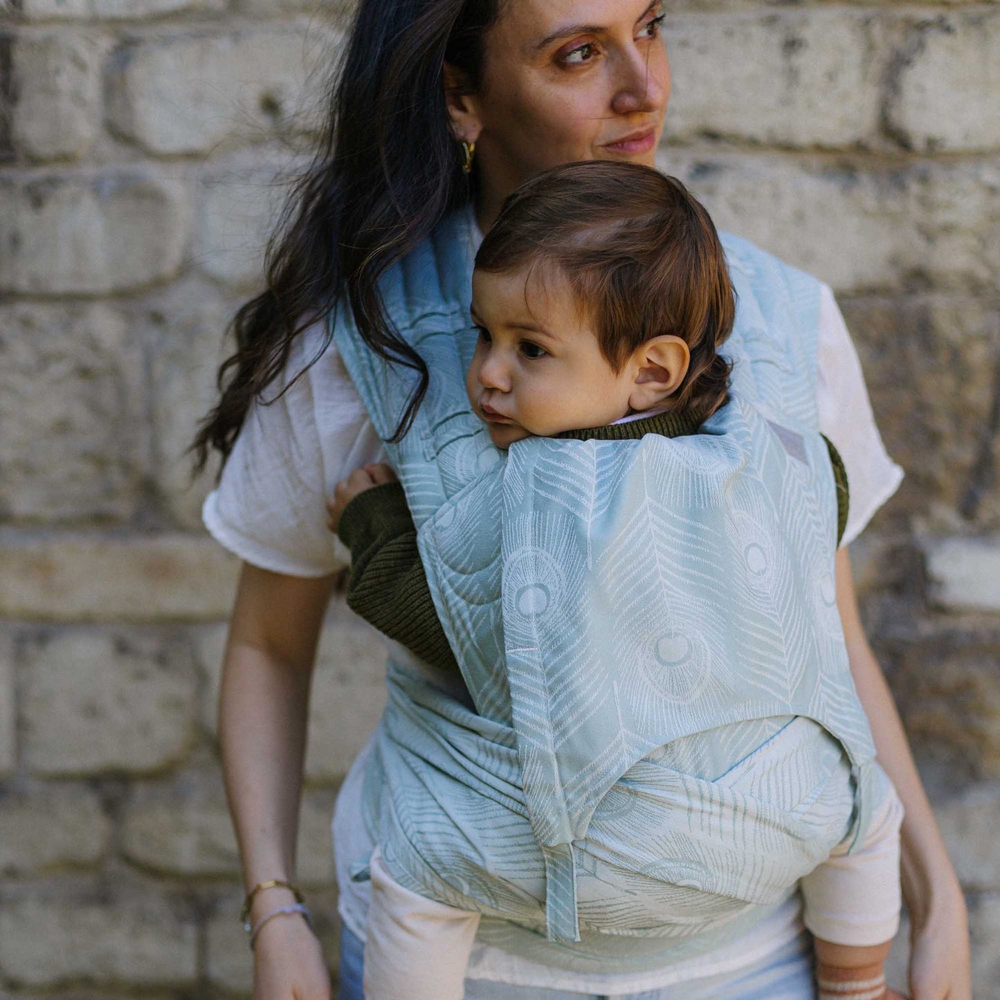 Un bébé est porté dans FlyClick Halfbuckle PorteBébé Design Feather blue