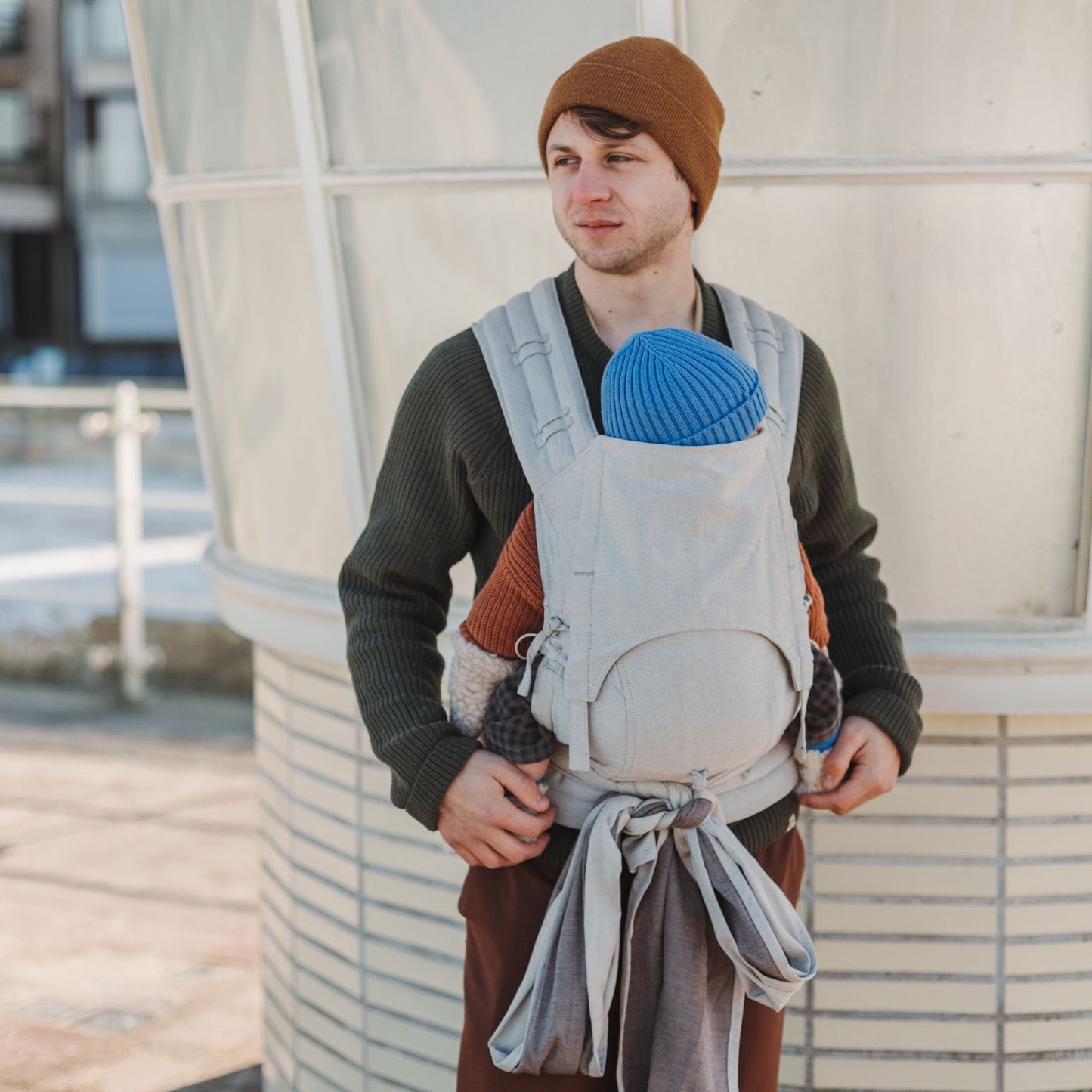 A baby is carried in Fly Tai Mei Tai Sling baby carrier Design Chevron cream