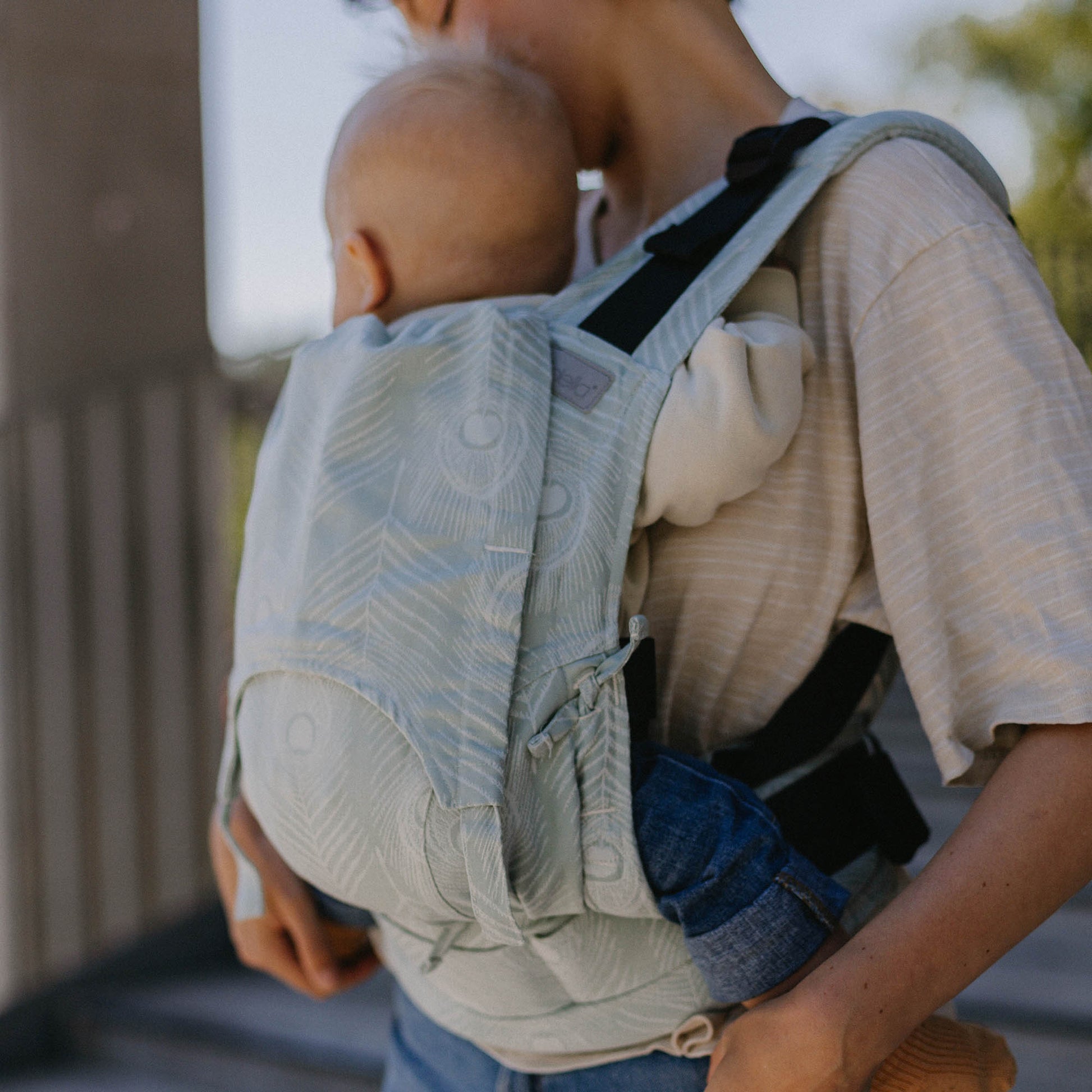 Un bebé es llevado en FullBuckle Mochila Ergonómica  con hebillas Design Feather  blue