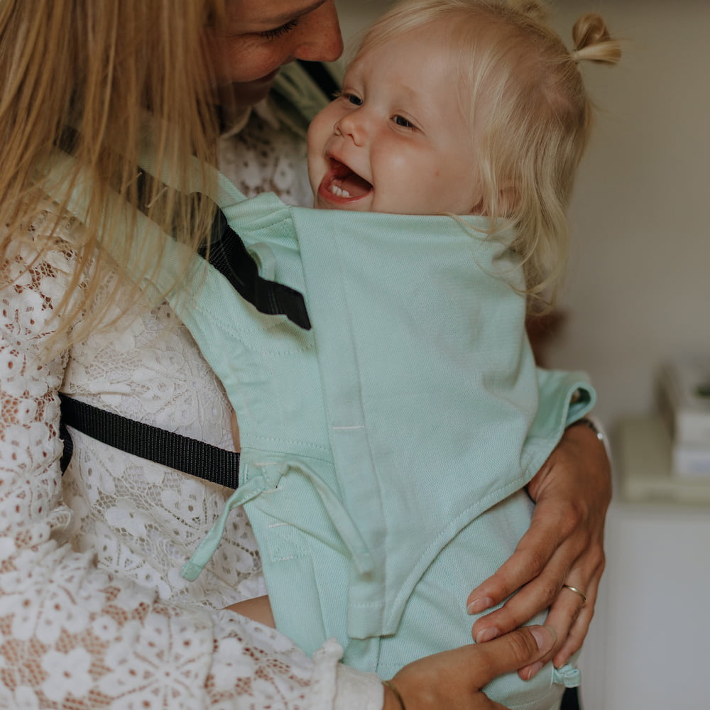 A baby is carried in Fusion Full Buckle Baby Carrier Design Chevron pastel mint