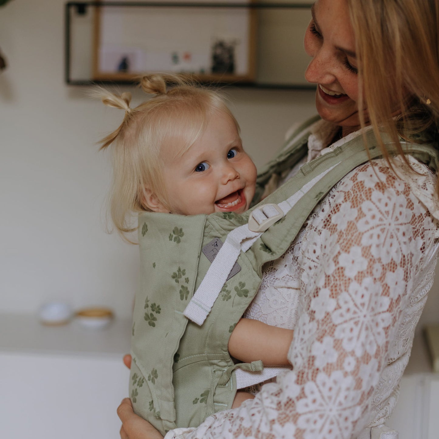 A toddler is carried in Fusion Full Buckle Baby Carrier Design Clover pale green