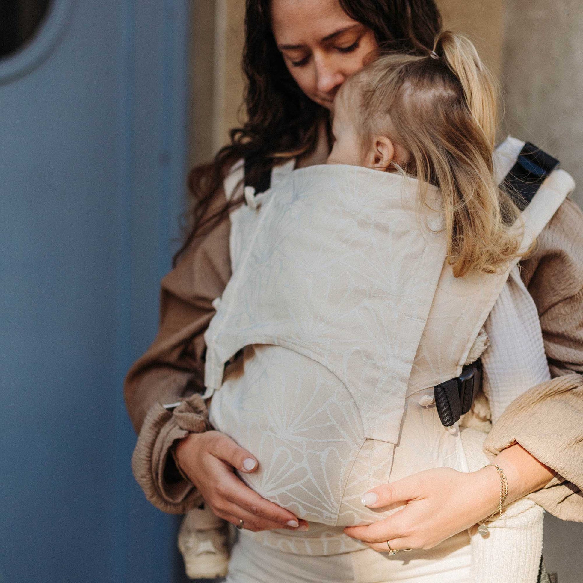 Llevan a un niño pequeño en FullBuckle Mochila Ergonómica  con hebillas Design Seashell  sand
