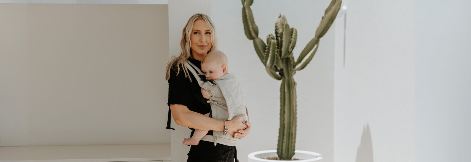 A mother is carrying her baby in a Fusion baby carrier in public