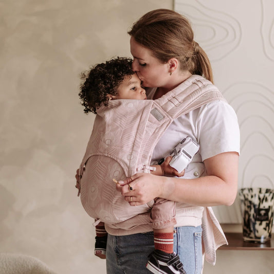 A toddler is carried in Fly Tai Mei Tai  Sling baby carrier Design Feather  rose